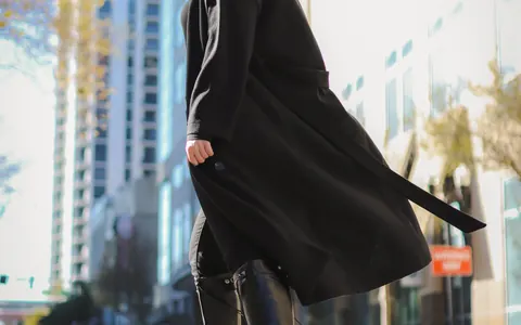 도심에서 긴 검정 코트와 검정 바지를 입은 여성